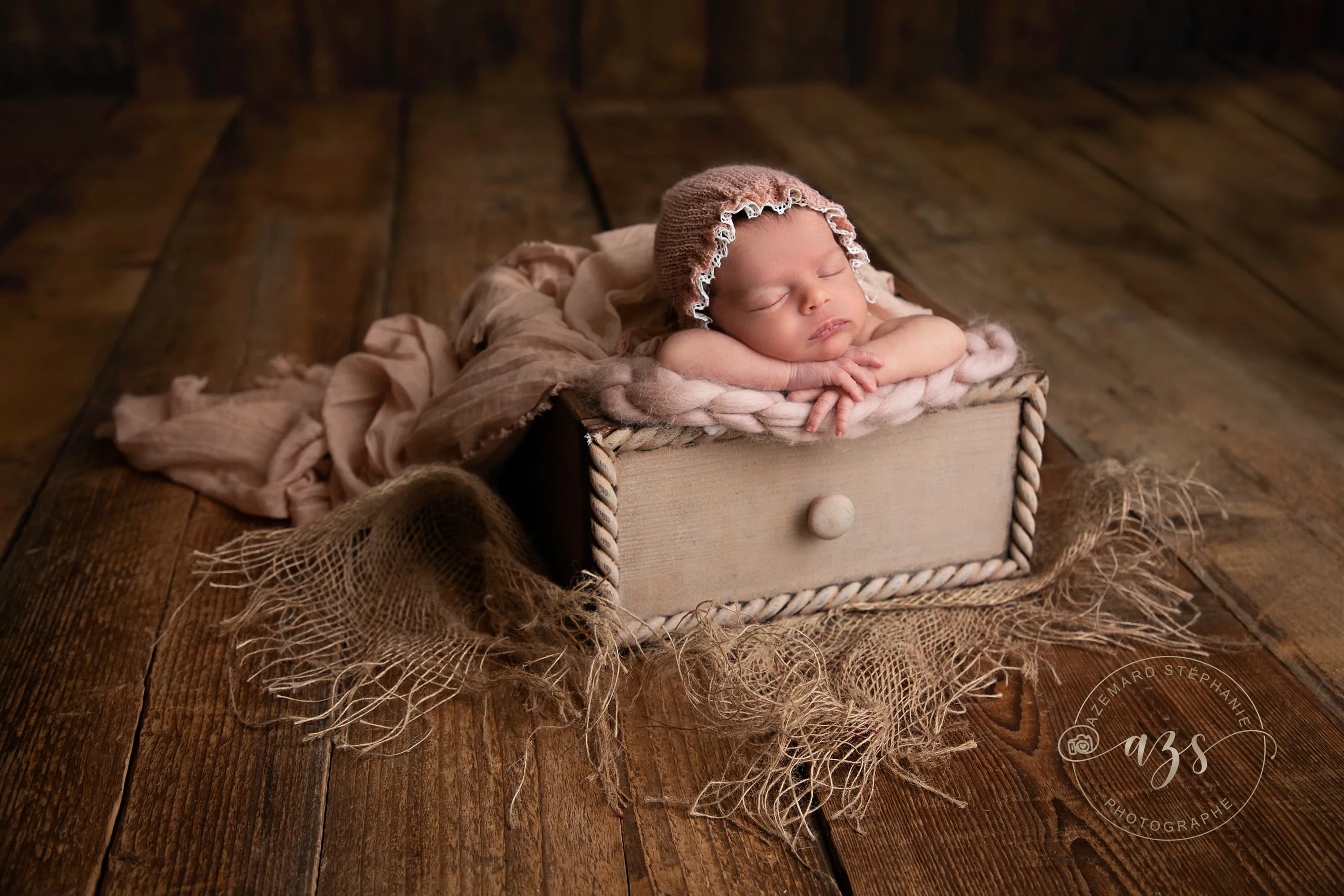 Photo nouveau-né endormi avec bonnet rose dans un décor bois, photographe maternité Montpellier Stéphanie Azémard