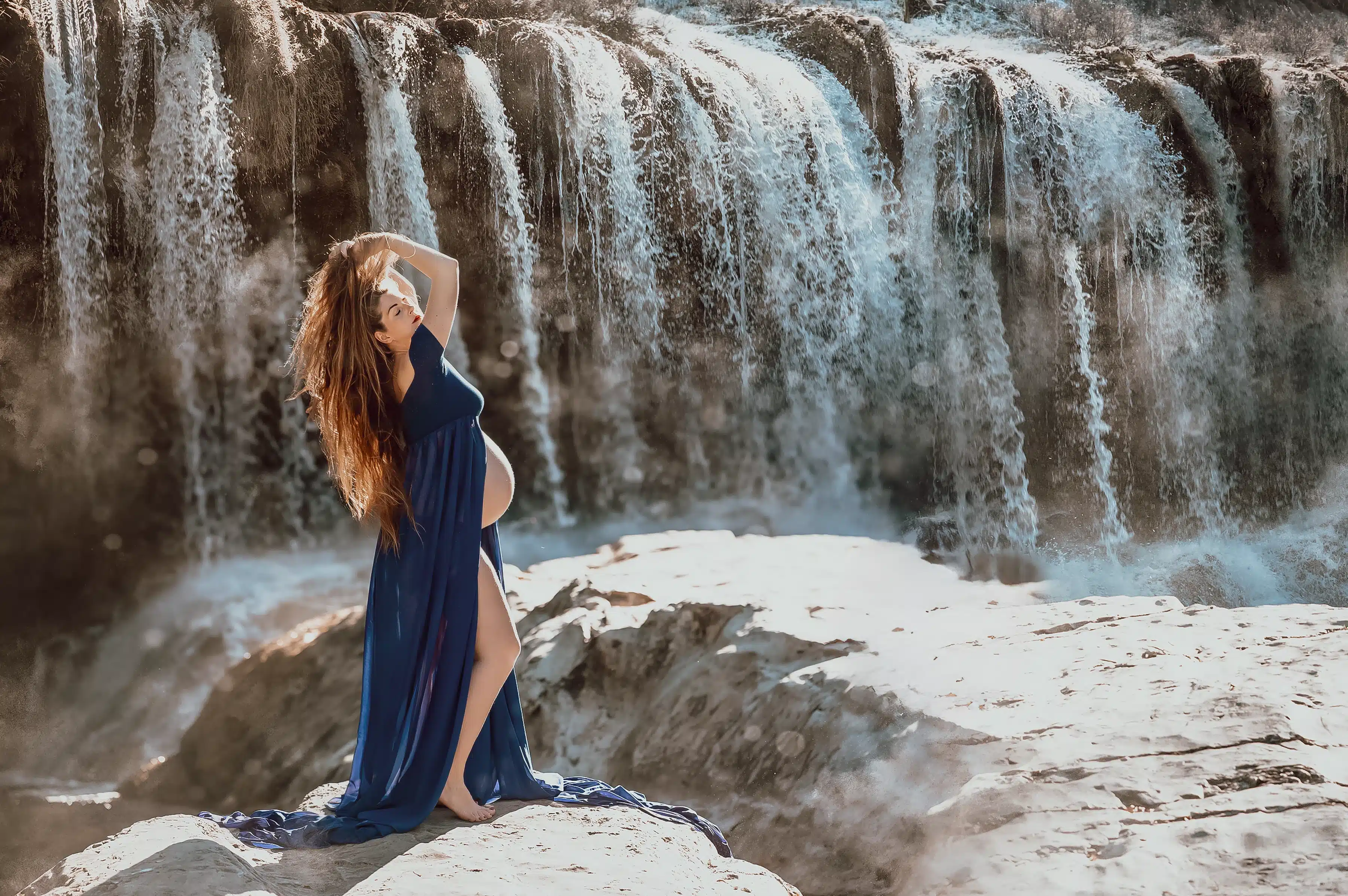 Séance photo grossesse en extérieur devant une cascade, femme enceinte en robe bleue, photographe maternité Montpellier