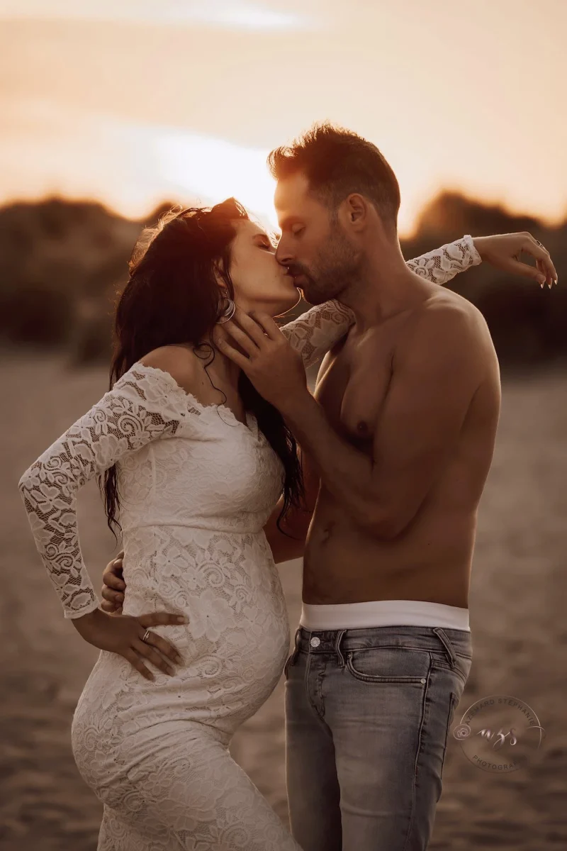 Photo grossesse couple qui s'embrasse sur la plage au coucher de soleil, future maman robe dentelle blanche, photographe maternité Montpellier Stéphanie Azémard