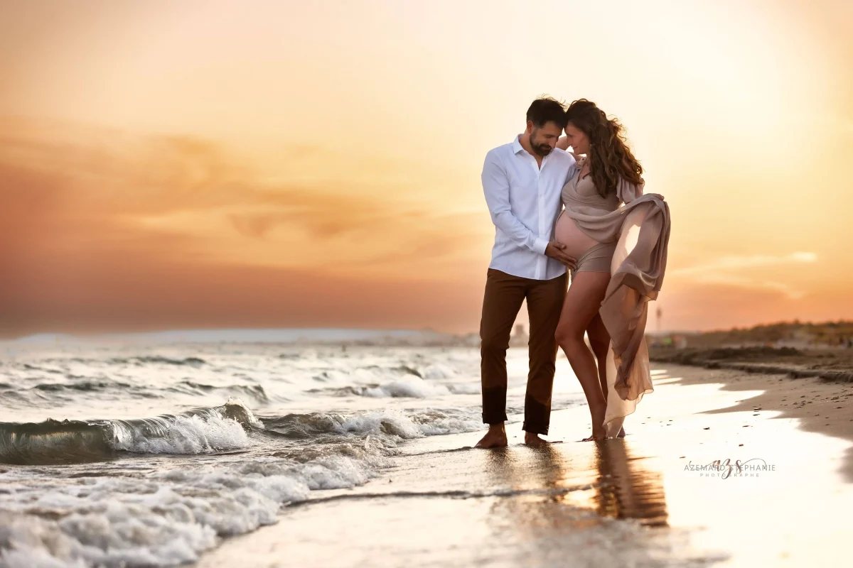 Photo grossesse couple enlacé sur la plage du Grand Travers au coucher de soleil, future maman voile beige, photographe maternité Montpellier Stéphanie Azémard