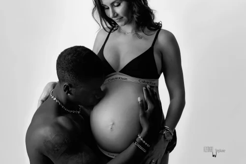© Stéphanie Azémard — Photographe maternité Montpellier Photo grossesse couple papa faisant un bisou sur le ventre de la future maman en noir et blanc studio fond blanc, photographe maternité Montpellier Stéphanie Azémard