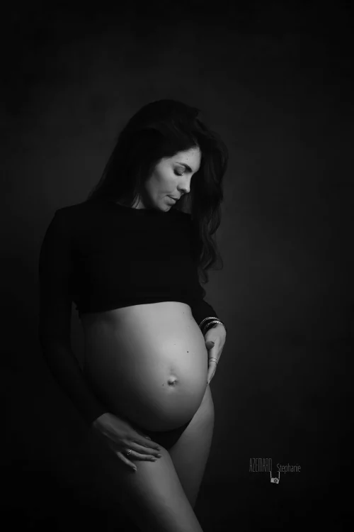 © Stéphanie Azémard — Photographe maternité Montpellier Photo grossesse future maman crop top noir ventre arrondi de profil en noir et blanc studio fond sombre, photographe maternité Montpellier Stéphanie Azémard