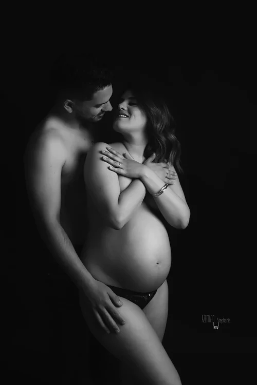 © Stéphanie Azémard — Photographe maternité Montpellier Photo grossesse couple complice future maman souriante ventre arrondi en noir et blanc studio fond noir, photographe maternité Montpellier Stéphanie Azémard