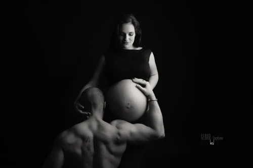© Stéphanie Azémard — Photographe maternité Montpellier Photo grossesse papa de dos tenant le ventre arrondi de la future maman en noir et blanc studio fond noir, photographe maternité Montpellier Stéphanie Azémard