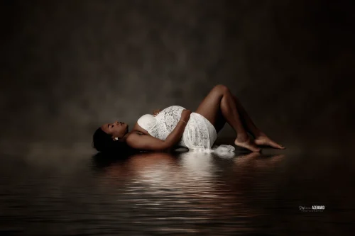 © Stéphanie Azémard — Photographe maternité Montpellier Photo grossesse future maman allongée en dentelle blanche avec reflet eau studio fond sombre, photographe maternité Montpellier Stéphanie Azémard