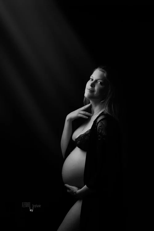 © Stéphanie Azémard — Photographe maternité Montpellier Photo grossesse future maman souriant regard caméra en noir et blanc studio fond noir, photographe maternité Montpellier Stéphanie Azémard