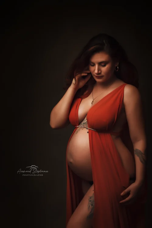 © Stéphanie Azémard — Photographe maternité Montpellier Photo grossesse future maman robe rouge drapée ceinture dorée tatouages en studio fond sombre, photographe maternité Montpellier Stéphanie Azémard
