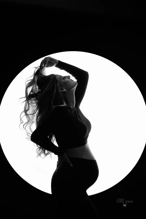 © Stéphanie Azémard — Photographe maternité Montpellier Photo grossesse silhouette future maman dans un cercle de lumière en noir et blanc studio, photographe maternité Montpellier Stéphanie Azémard