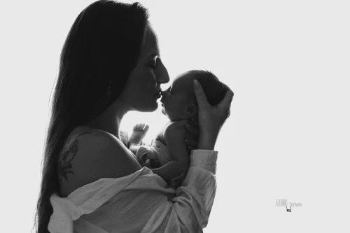 © Stéphanie Azémard — Photographe maternité Montpellier Photo maman faisant un bisou à son nouveau-né en silhouette contre-jour noir et blanc fond blanc, photographe maternité Montpellier Stéphanie Azémard