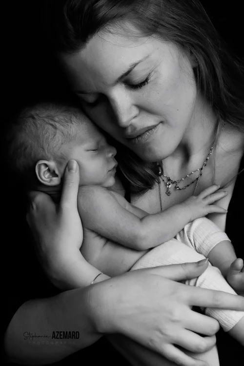 © Stéphanie Azémard — Photographe maternité Montpellier Portrait maman souriante tenant son nouveau-né endormi contre elle en noir et blanc studio, photographe maternité Montpellier Stéphanie Azémard