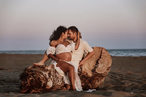 © Stéphanie Azémard — Photographe maternité Montpellier Photo grossesse couple assis sur tronc bois flottée plage au coucher de soleil, future maman dentelle blanche, photographe maternité Montpellier Stéphanie Azémard