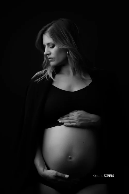 © Stéphanie Azémard — Photographe maternité Montpellier Portrait grossesse future maman tenant son ventre arrondi en noir et blanc studio fond noir, photographe maternité Montpellier Stéphanie Azémard