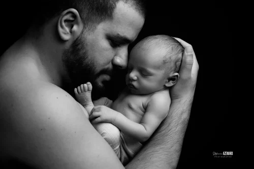 © Stéphanie Azémard — Photographe maternité Montpellier Photo nouveau-né endormi contre la joue de son papa en noir et blanc studio, photographe maternité Montpellier Stéphanie Azémard
