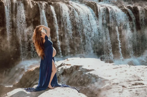 Séance grossesse en pleine nature — Stéphanie Azémard photographe maternité Montpellier Séance photo grossesse en extérieur devant une cascade, femme enceinte en robe bleue, photographe maternité Montpellier