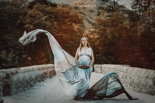 Séance grossesse poétique et féerique — Stéphanie Azémard photographe maternité Montpellier Séance photo grossesse femme enceinte en robe bleue volante sur un pont en pierre avec couronne de fleurs, photographe maternité Montpellier