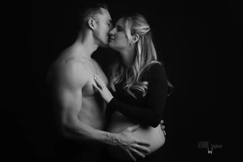 © Stéphanie Azémard — Photographe maternité Montpellier Photo grossesse couple qui s'embrasse en studio fond noir noir et blanc, future maman ventre arrondi, photographe maternité Montpellier Stéphanie Azémard