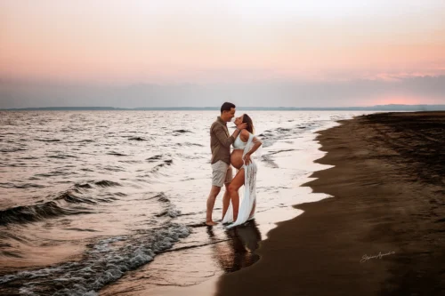 Couple enlacé sur la plage au coucher du soleil, ciel rose