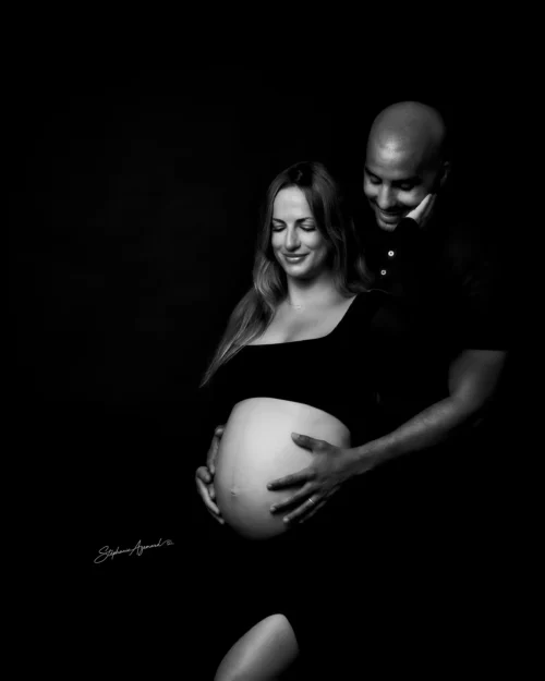 Couple regardant tendrement le ventre rond, portrait noir et blanc