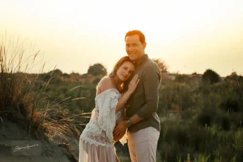 Couple souriant à l'objectif pendant la golden hour dans les dunes
