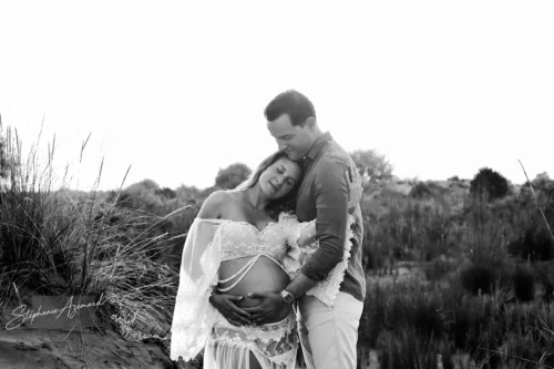 Étreinte d'un couple dans les dunes, photo grossesse noir et blanc