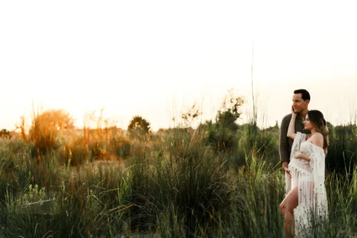 Couple au milieu des herbes au coucher du soleil, plan large